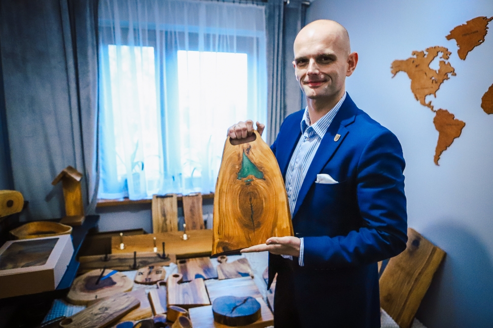 Sylwester Ziemkiewicz z deską do krojenia wykonaną z drewna