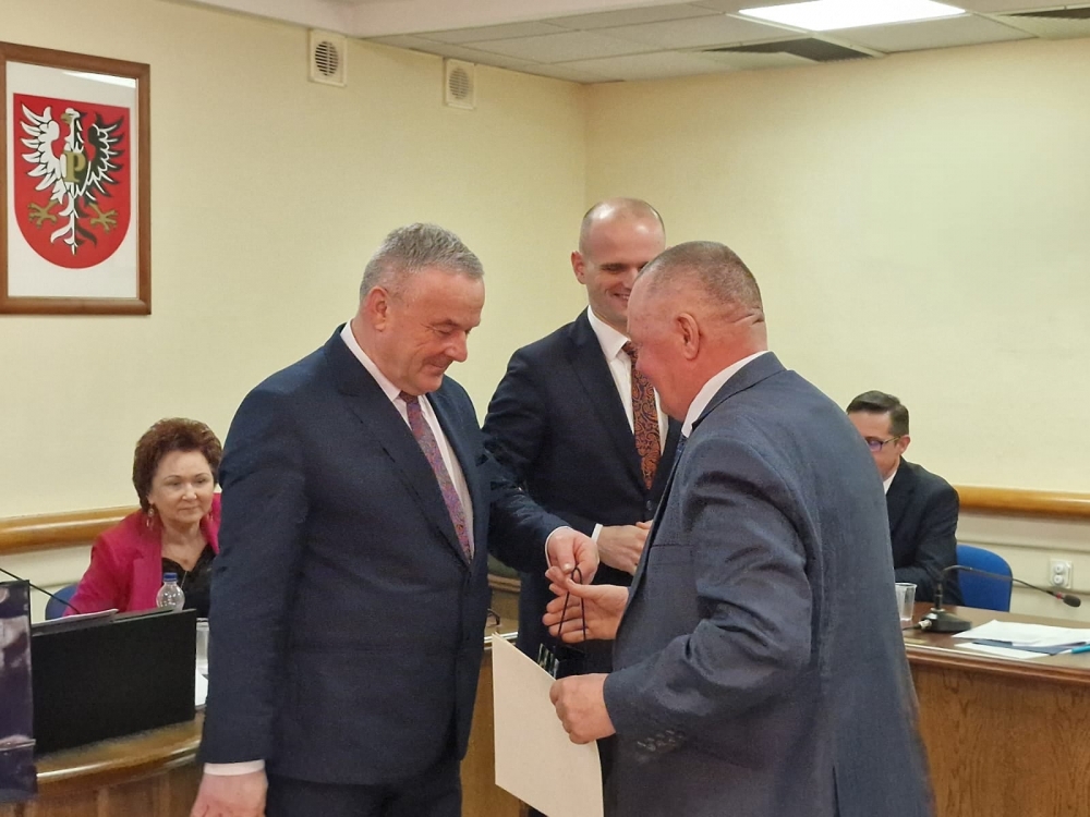Przewodniczący rady powiatu wręczający upominki radnemu