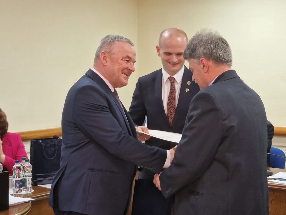 Starosta i przewodniczący rady powiatu wręczający podziękowania