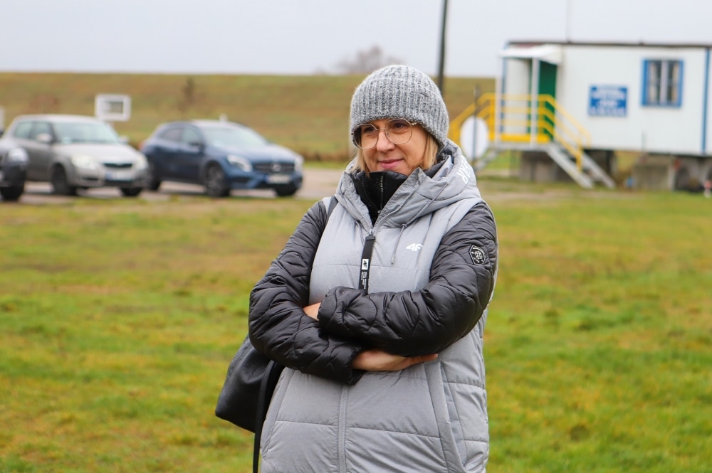 Kobieta w kurtce nad brzegiem rzeki.