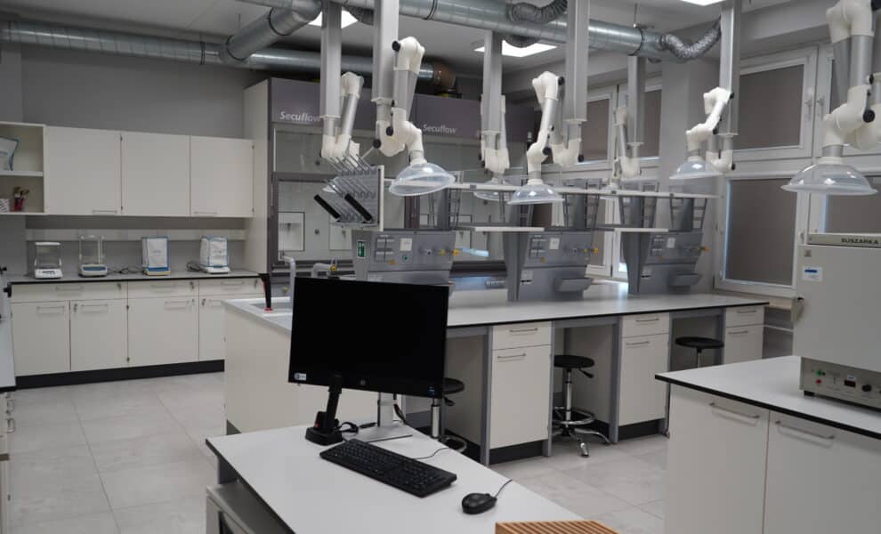 Nowoczesne laboratorium chemiczne wyposażone w sprzęt analityczny i stanowiska pracy.