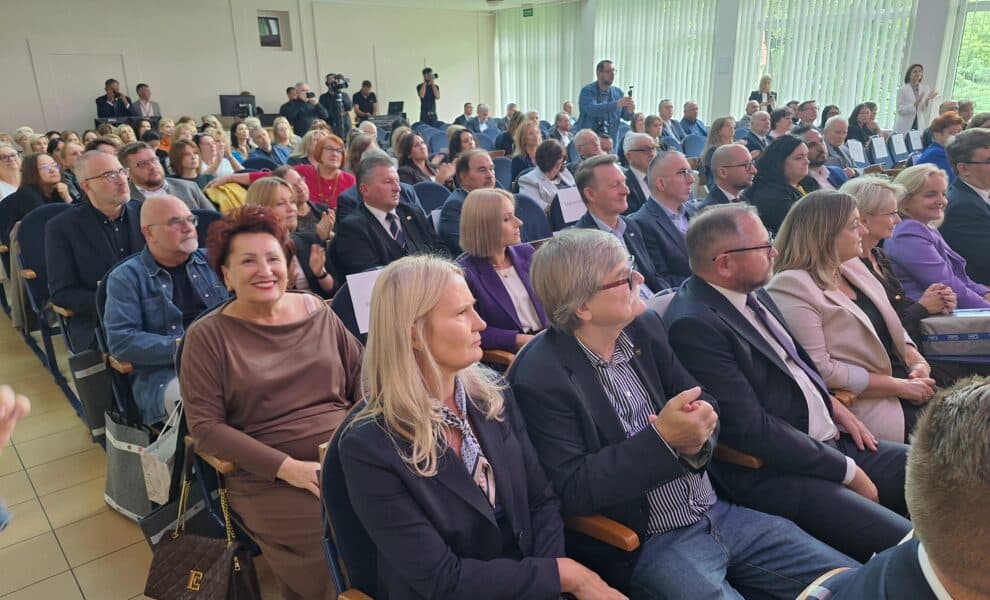 Na zdjęciu widoczna jest tłumnie zgromadzona sala podczas wydarzenia, w której uczestnicy siedzą w rzędach, niektórzy z nich są uśmiechnięci.