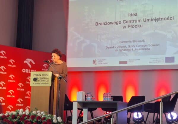 Na zdjęciu Małgorzata Struzik Dyrektor Wydziału Edukacji, Kultury i Spraw Społecznych Starostwa Powiatowego w Płocku przemawiającą na konferencji w Zespole Szkół Centrum Edukacji im. Ignacego Łukasiewicza, z tłem ozdobionym logiem Orlen.