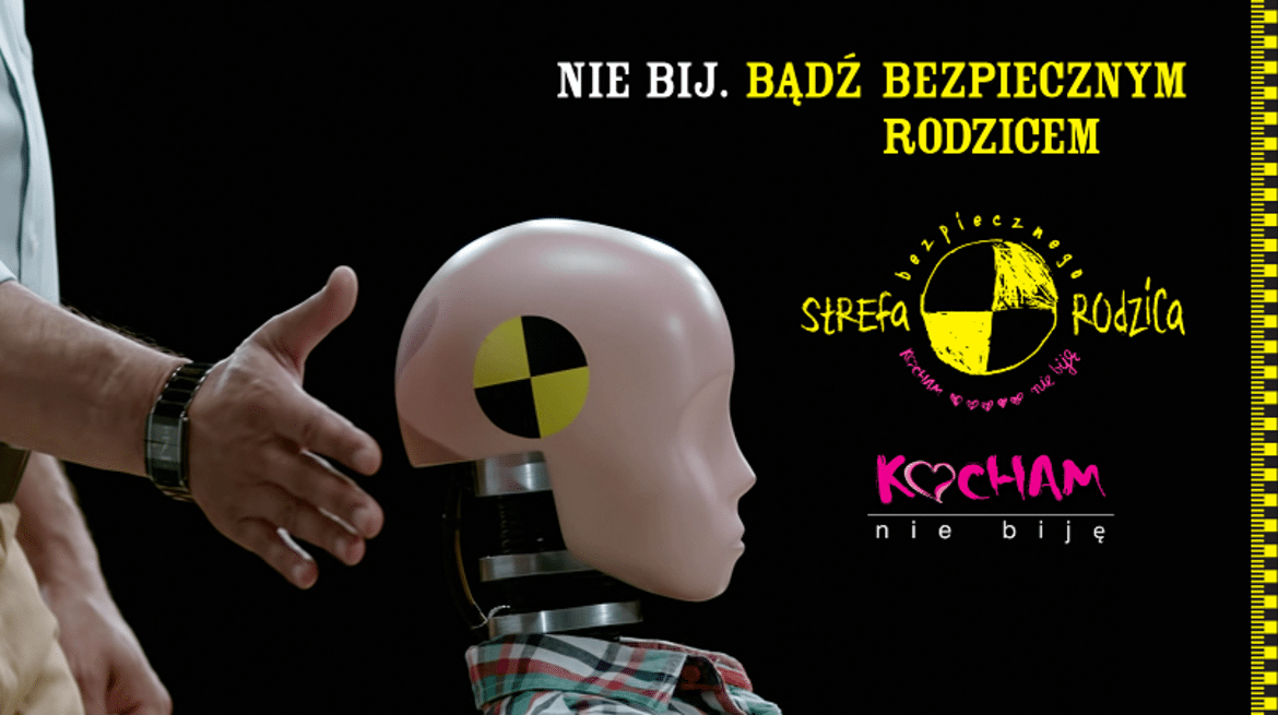 Zbliżenie na manekina dziecięcego, któremu towarzyszy dłoń dorosłego, z hasłami promującymi bezpieczeństwo i zakaz przemocy.