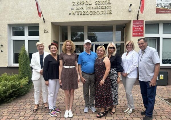 Grupa osób stoi przed budynkiem Zespołu Szkół im. Jana Śniadeckiego w Wyszogrodzie.
