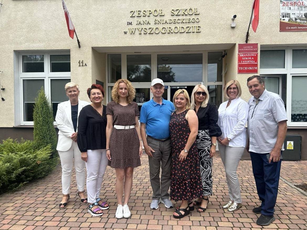 Grupa osób stoi przed budynkiem Zespołu Szkół im. Jana Śniadeckiego w Wyszogrodzie.