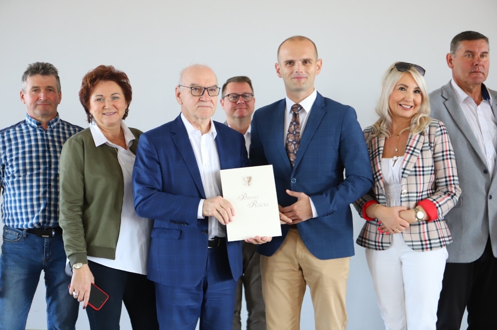 Grupa osób pozująca do zdjęcia z dokumentem przedstawiającym nowo wyremontowane drogi w gminach Nowy Duninów i Gubin.