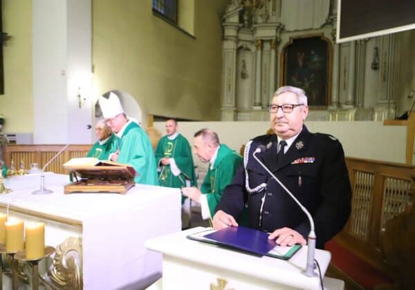 Na zdjęciu widoczna jest ceremonia w kościele, w której uczestniczy kilku duchownych w zielonych szatach liturgicznych oraz funkcjonariusz w mundurze stojący obok ołtarza.