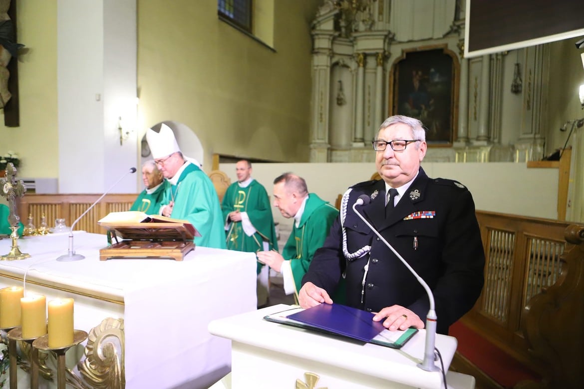 Na zdjęciu widoczna jest ceremonia w kościele, w której uczestniczy kilku duchownych w zielonych szatach liturgicznych oraz funkcjonariusz w mundurze stojący obok ołtarza.