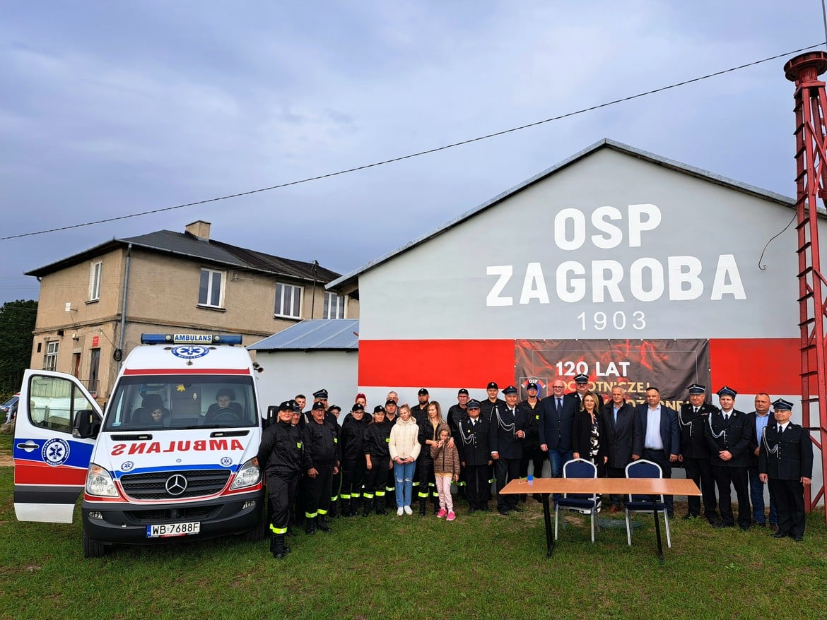 Na zdjęciu widoczna jest grupa ludzi, w tym przedstawiciele straży pożarnej, zgromadzona przed budynkiem OSP Zagroba z okazji 120-lecia tej jednostki.