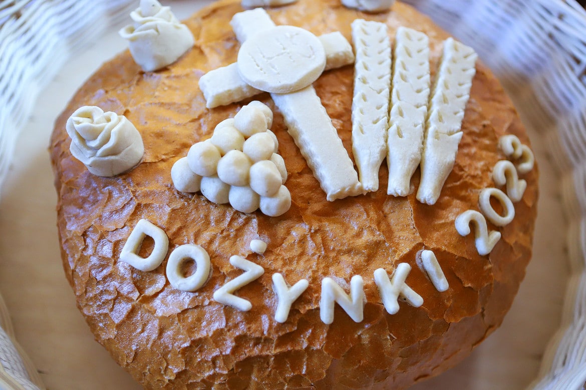 Chleb dożynkowy ozdobiony ornamentami w postaci krzyża, kłosów, winogron oraz napisu "Dożynki 2023".
