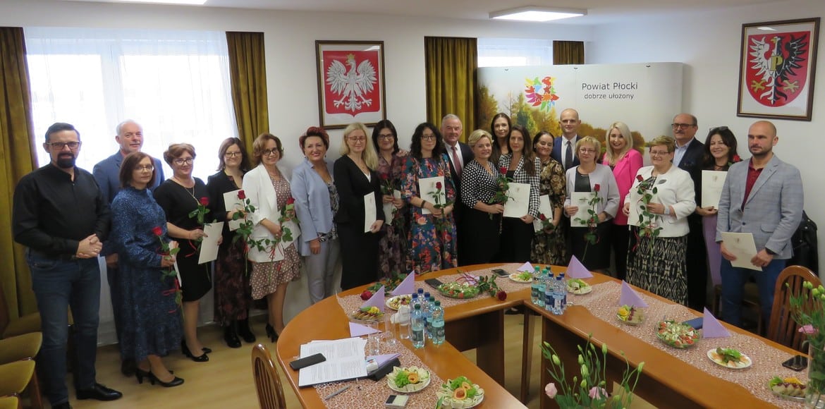 Grupa nauczycieli i pracowników oświaty świętuje XXV Powiatowy Dzień Edukacji Narodowej w siedzibie Starostwa Powiatowego w Płocku, trzymając kwiaty i dyplomy.
