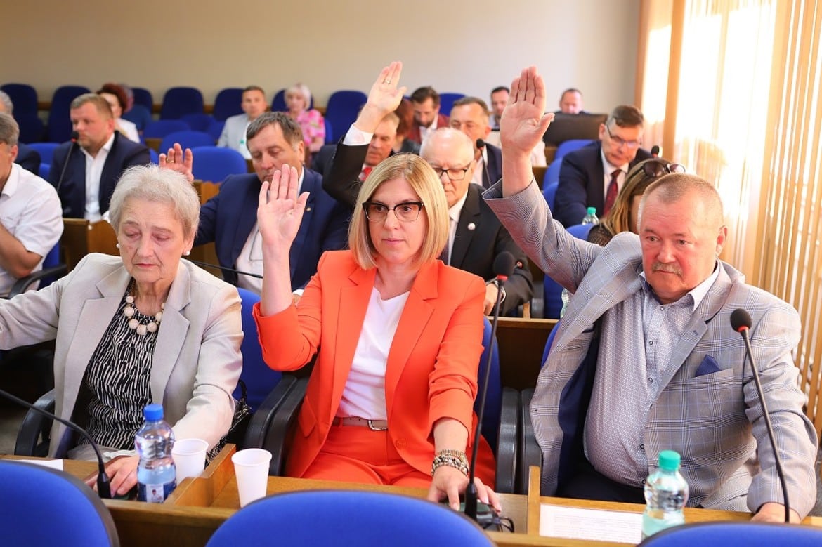 Na zdjęciu widać radnych podnoszących ręce podczas głosowania na sesji.