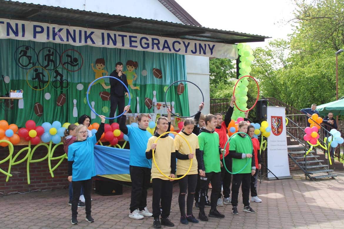 Na zdjęciu widoczna jest grupa młodzieży w kolorowych koszulkach, prezentująca występ w trakcie wydarzenia pod hasłem "Integracyjny Piknik".