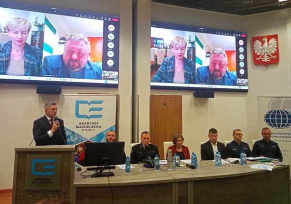 Zdjęcie przedstawia spotkanie w Akademii Mazowieckiej w Płocku, z osobami uczestniczącymi zarówno na żywo, jak i zdalnie, które omawiają ważne tematy.