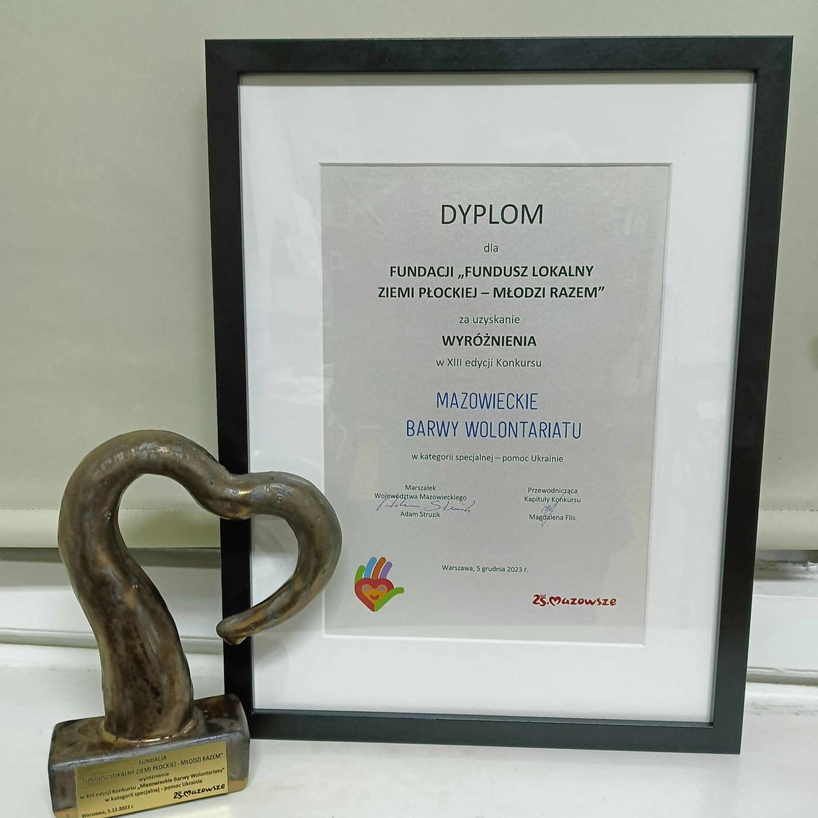 Na zdjęciu znajduje się dyplom oraz statuetka, które zostały przyznane Fundacji „Fundusz Lokalny Ziemi Płockiej - Młodzi Razem” za wyróżnienie w XIII edycji Konkursu „Mazowieckie Barwy Wolontariatu”.