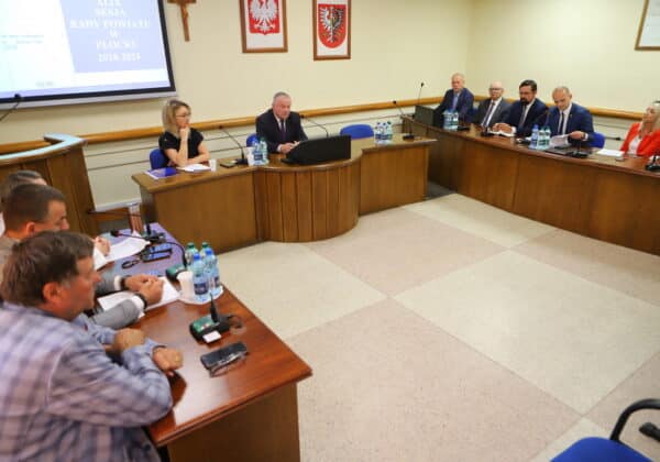 Zebranie członków Rady Powiatu w Płocku, omawiających istotne sprawy na sesji w sali konferencyjnej.