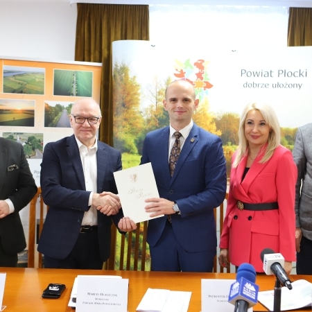 Na zdjęciu widoczna jest grupa ludzi podczas ceremonii podpisania dokumentu, przedstawiająca władze powiatu płockiego.