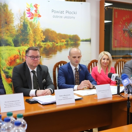 Na zdjęciu czterech mężczyzn i jedna kobieta siedzą przy stole podczas konferencji prasowej w Powiecie Płockim.