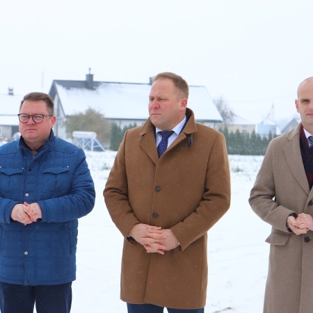 Na zdjęciu trzech mężczyzn stoi na zaśnieżonym terenie, podczas wydarzenia związanego z otwarciem inwestycji drogowej.