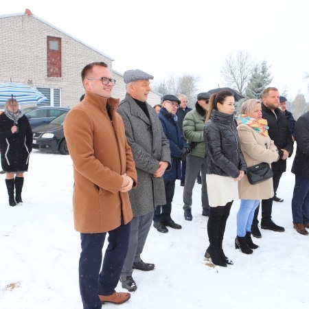 Na zdjęciu widoczna jest grupa osób stojących w śniegu, w większości ubranych w ciepłe kurtki, w trakcie otwarcia inwestycji drogowej.