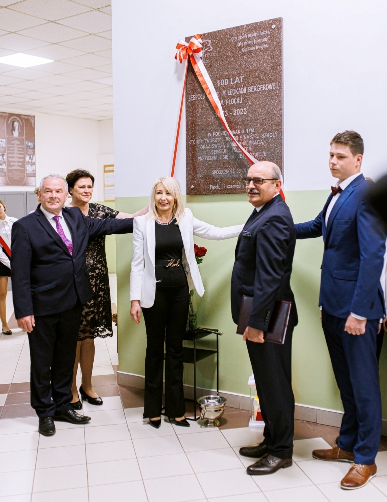 Na zdjęciu widać grupę osób zgromadzonych wokół tablicy pamiątkowej z okazji 100-lecia Zespołu Szkół im. Leokadii Bergerowej w Płocku.