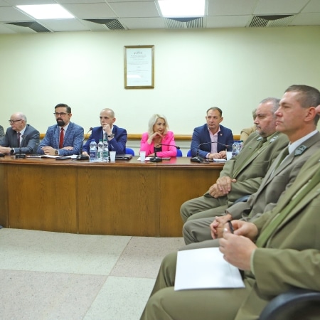 Na zdjęciu widać grupę osób uczestniczących w posiedzeniu rady powiatu, siedzących przy stole w sali konferencyjnej.