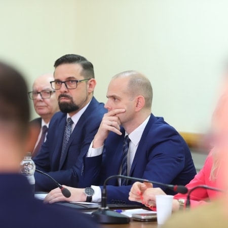 Na zdjęciu grupa mężczyzn i kobiet uczestniczy w sesji rady powiatu, koncentrując się na dyskusji.