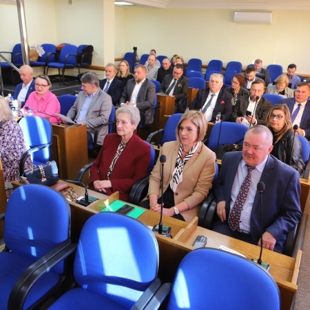 Na zdjęciu widać grupę osób siedzących w sali obrad, uczestniczących w sesji rady powiatu.