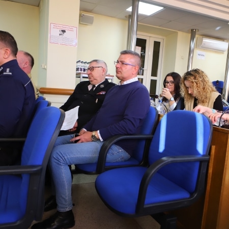 Na zdjęciu widoczni są uczestnicy sesji rady powiatu w Płocku, siedzący w niebieskich fotelach, z różnorodnymi dokumentami i materiałami w rękach.