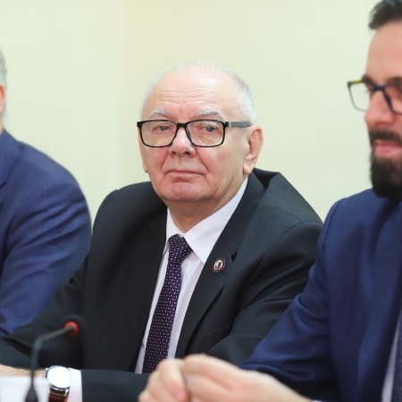 Zdjęcie przedstawia trzech mężczyzn siedzących przy stole podczas sesji rady powiatu.