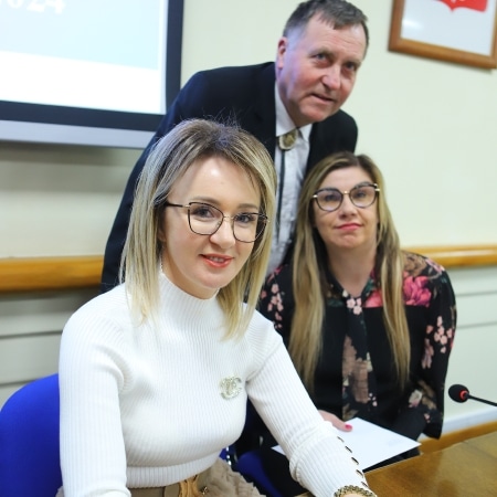 Na zdjęciu przedstawiono trzech uczestników sesji Rady Powiatu w Płocku, którzy siedzą przy stole, w towarzystwie prezentacji na ekranie w tle.