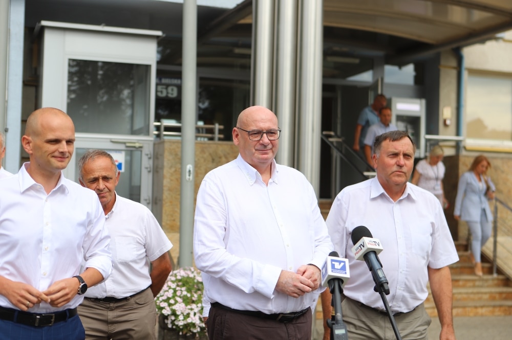 Na zdjęciu grupa mężczyzn w białych koszulach stoi przed budynkiem, podczas konferencji prasowej dotyczącej sytuacji rolników.