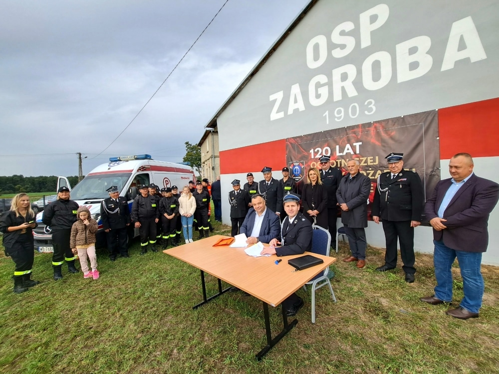 Na zdjęciu przedstawiono uroczystość podpisania dokumentu związanego z 120-leciem OSP Zagrobnica, podczas której zebrali się członkowie ochotniczej straży pożarnej oraz zaproszeni goście.