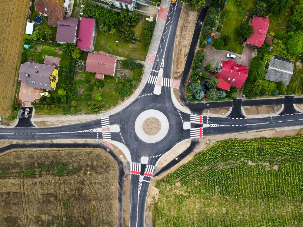 Widok z góry na nowo wybudowane rondo otoczone domami i terenami zielonymi.