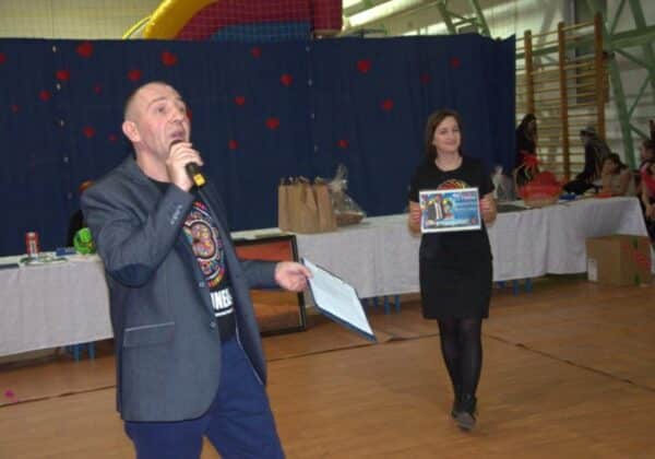 Na zdjęciu widać mężczyznę przemawiającego do mikrofonu oraz kobietę trzymającą plakat, podczas finału Wielkiej Orkiestry Świątecznej Pomocy.