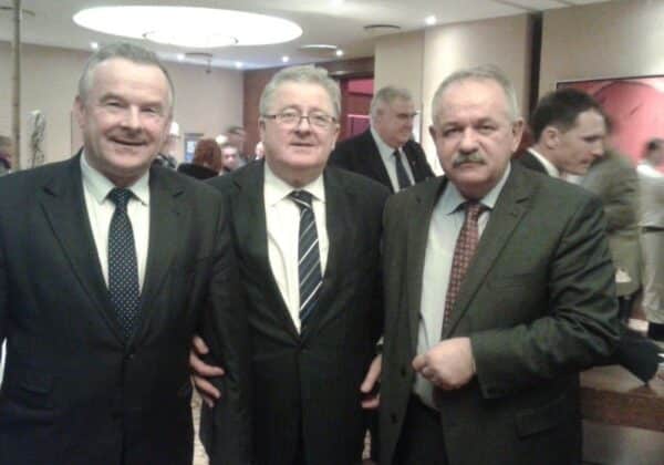 Trzech mężczyzn w eleganckich garniturach pozujące razem na zakończenie gali konkursu Rolnik-Farmer Roku.