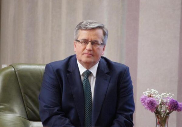 Prezydent RP Bronisław Komorowski podczas wizyty w Płocku, siedzący w biurze przy bukiecie kwiatów.