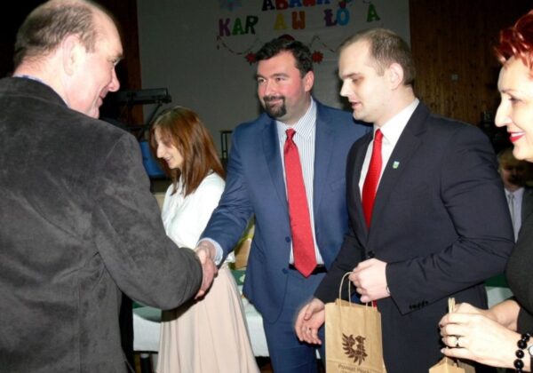 Noworoczne spotkanie w Radzanowie, podczas którego uczestnicy witają się i wymieniają upominkami.