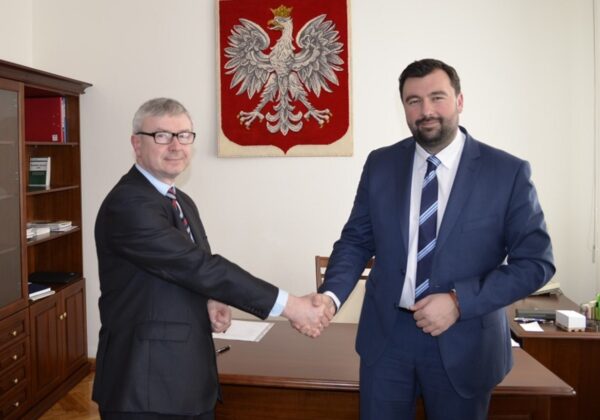 Spotkanie ze Starostą Gostynińskim, przedstawiające dwóch mężczyzn uściszczających sobie dłonie w biurze.