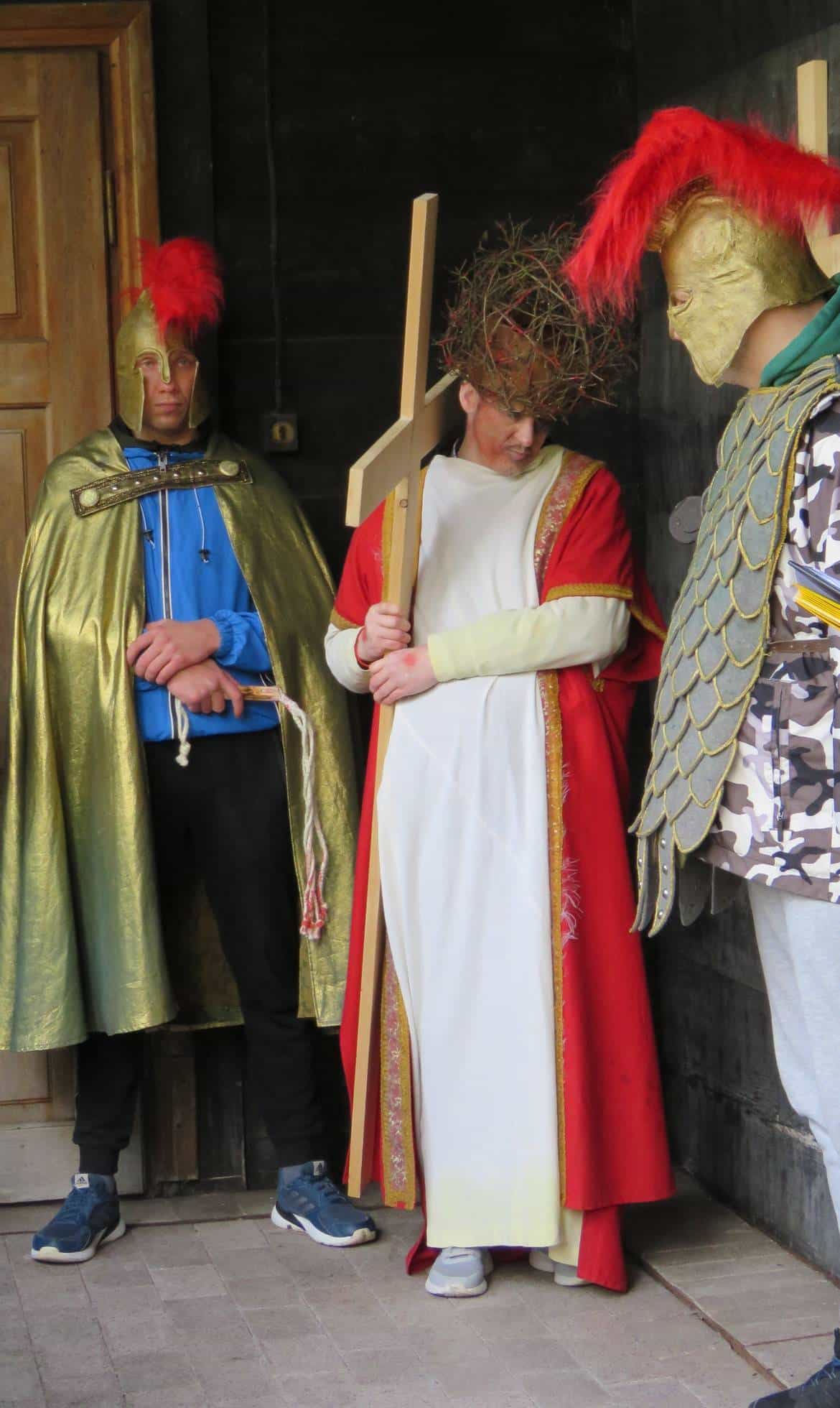 Na zdjęciu widoczna jest scena przedstawiająca postacie w strojach historycznych, w tym postaci z krzyżem oraz żołnierzy z hełmami, stojących w wejściu do budynku.