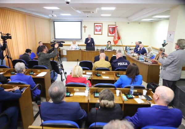 Na zdjęciu widać salę obrad, w której odbywa się spotkanie, z uczestnikami siedzącymi w rzędach oraz prelegentem występującym na podium.