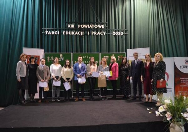 Na zdjęciu znajduje się grupa osób stojących na scenie podczas XIII Powiatowych Targów Edukacji i Pracy w 2023 roku.