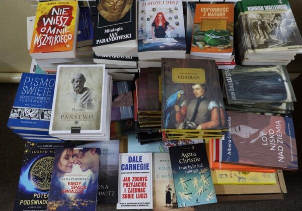 Stos książek różnych gatunków, w tym klasyki literatury i poradników, ułożony na stole.