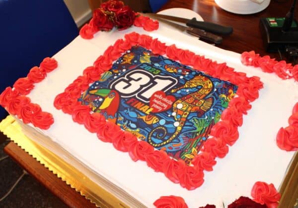 Na zdjęciu znajduje się tort ozdobiony czerwoną polewą i kolorowym nadrukiem z logo 31. Finału Wielkiej Orkiestry Świątecznej Pomocy.