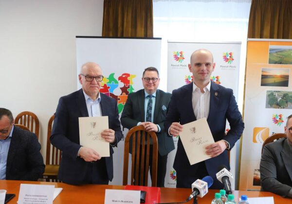Na zdjęciu przedstawiono trzech mężczyzn podczas uroczystości podpisania dokumentów związanych z Powiatem Płockim.