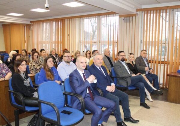 Na zdjęciu przedstawiono grupę osób uczestniczących w spotkaniu w sali konferencyjnej.