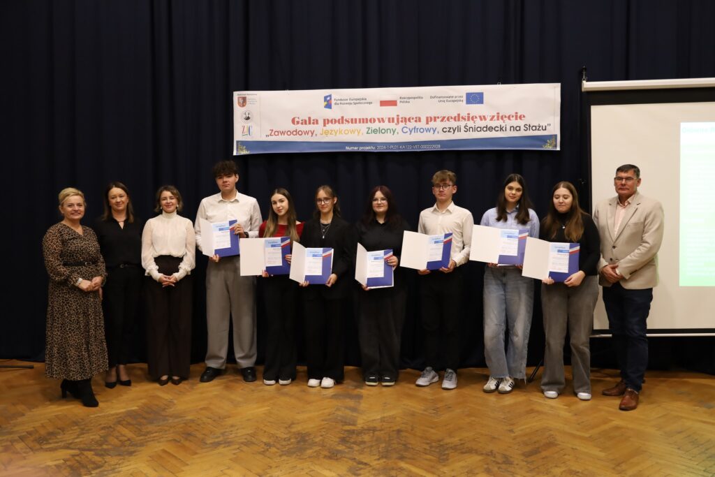 Uczestnicy gali podsumowującej przedsięwzięcie FERS „Zawodowy, Językowy, Zielony, Cyfrowy, czyli Śniadecki na Stażu” prezentują swoje dyplomy.