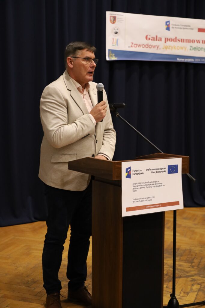 Na zdjęciu widać mężczyznę mówiącego do mikrofonu podczas gali podsumowującej projekt FERS „Zawodowy, Językowy, Zielony, Cyfrowy, czyli Śniadecki na Stażu”.