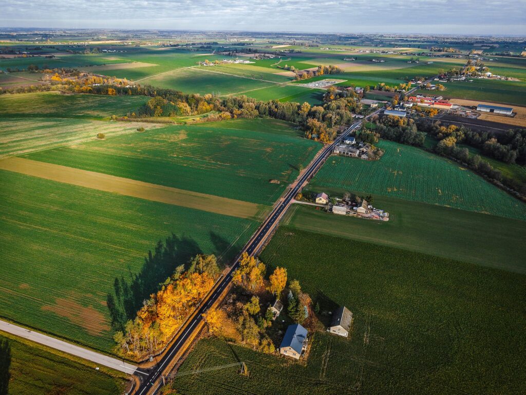Panorama ukazująca nową drogę oraz dwa mosty w otoczeniu malowniczych pól i zabudowań, symbolizująca długo oczekiwaną inwestycję.
